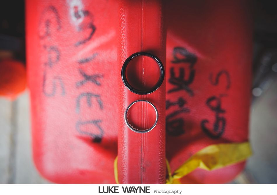 Two wedding rings, one black and one silver, atop a red gas can.