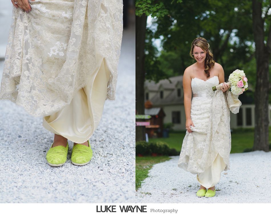 Bride in wedding dress, smiles, holding bouquet, shows neon green shoes on gravel path.