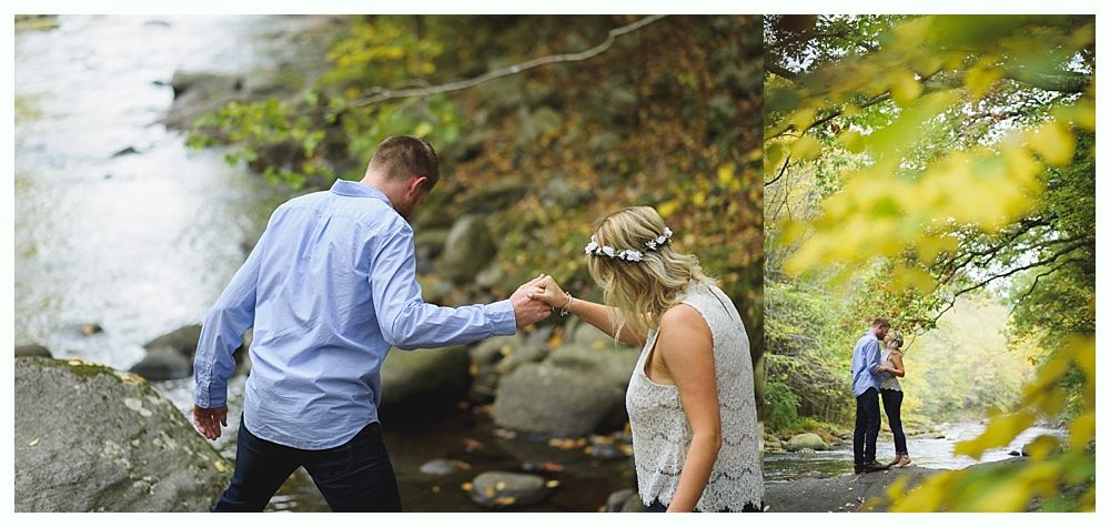 Couple holding hands, crossing a stream. Forest background with green and yellow foliage.