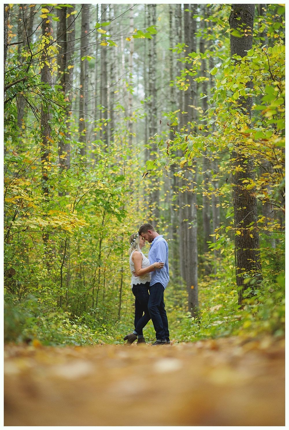 Couple embracing on a path in a green forest, soft focus.