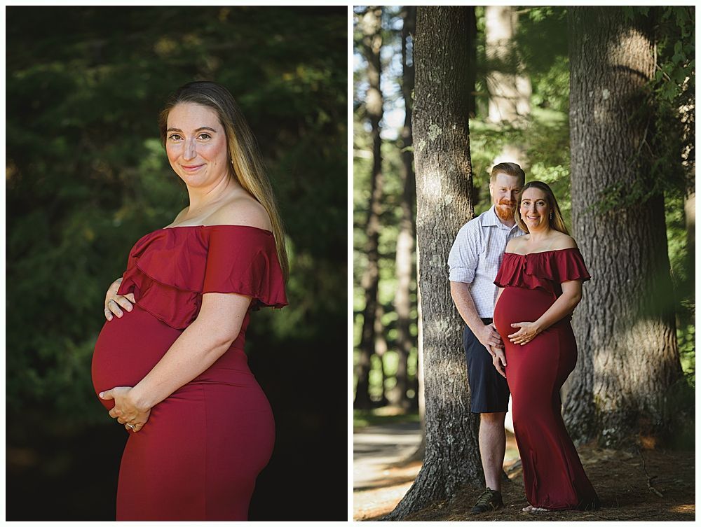 Pregnant woman in red dress, holds her belly. Couple poses by trees in a forest.
