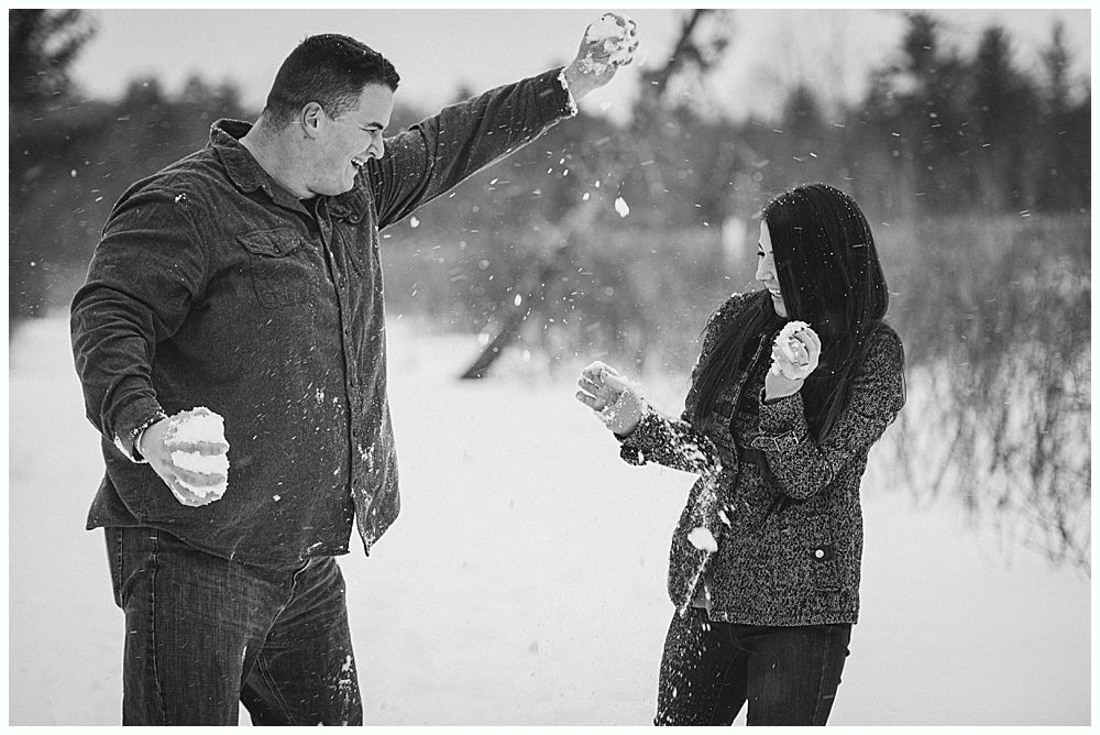 Man throwing a snowball at a person with a hood, both in a snowy field.