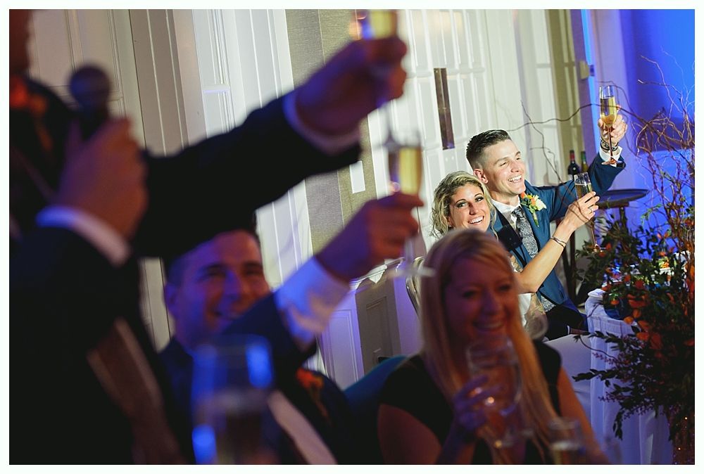 People toasting with champagne flutes at a wedding reception; happy faces and festive atmosphere.