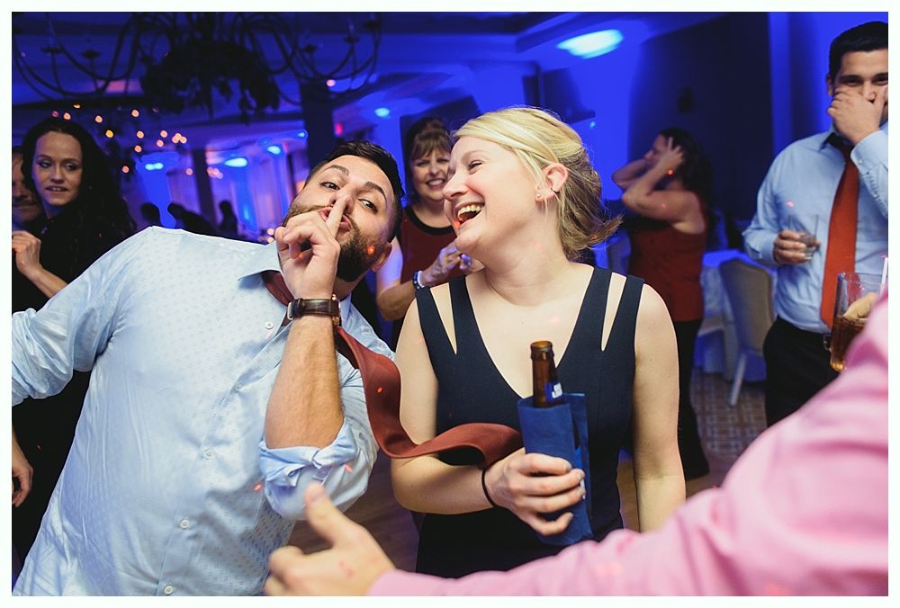 Man in patterned suit dances with a child on a lit dance floor. Other people dance in the background.