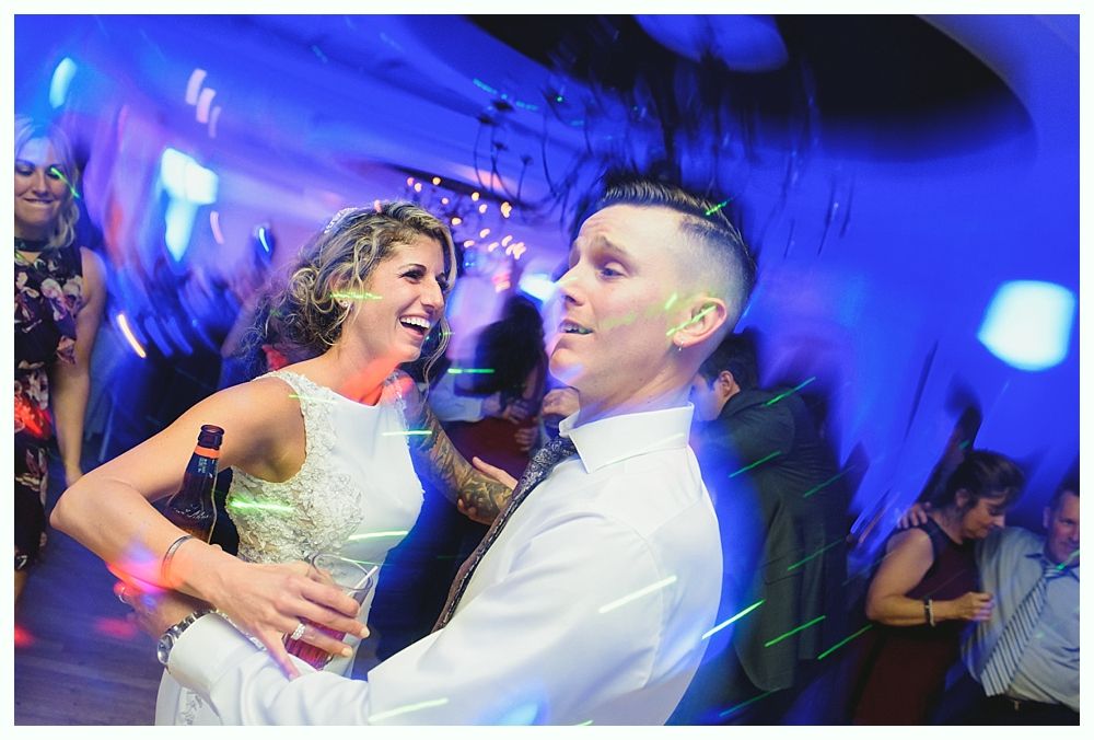 Couple dances at a party; blue and green light streaks across the scene.