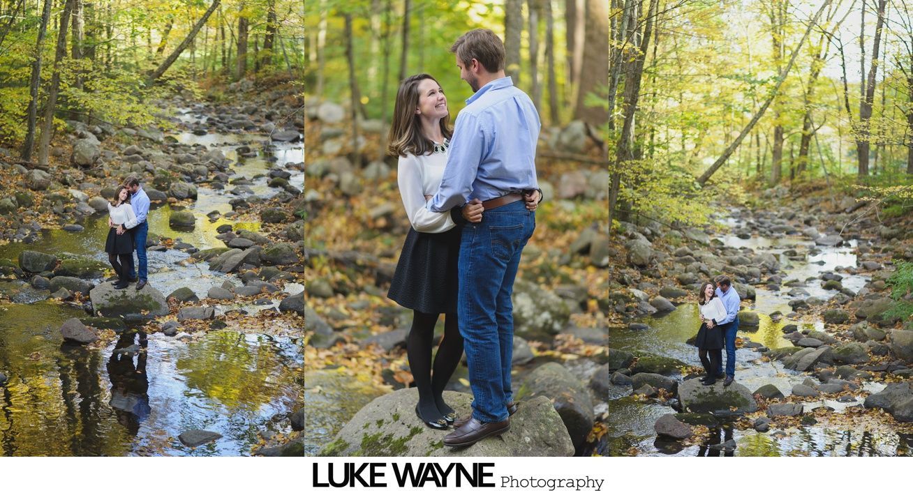 Couple embracing near stone columns in garden setting. Man in light blue shirt and shorts, woman in patterned dress.