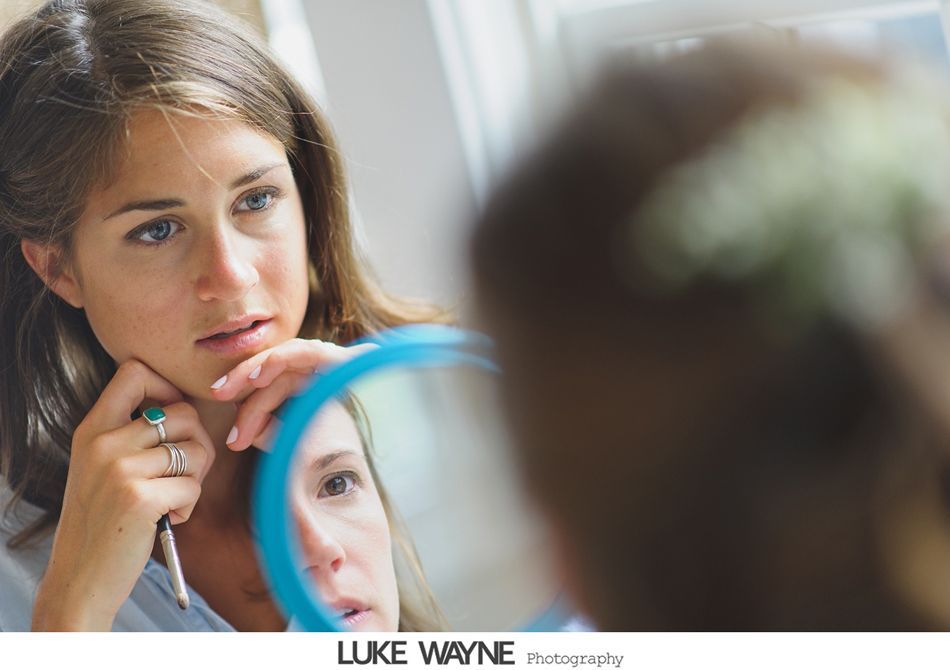 Woman looking in a mirror, touching her chin with a tweezer, indoors.