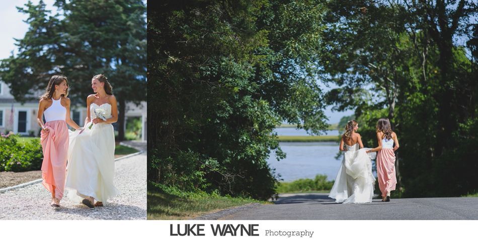 Two women, one in a white dress, the other in pink, walk together along a path in a park-like setting.