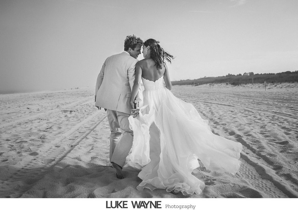 Bride and groom walking on a sandy beach after a wedding ceremony.