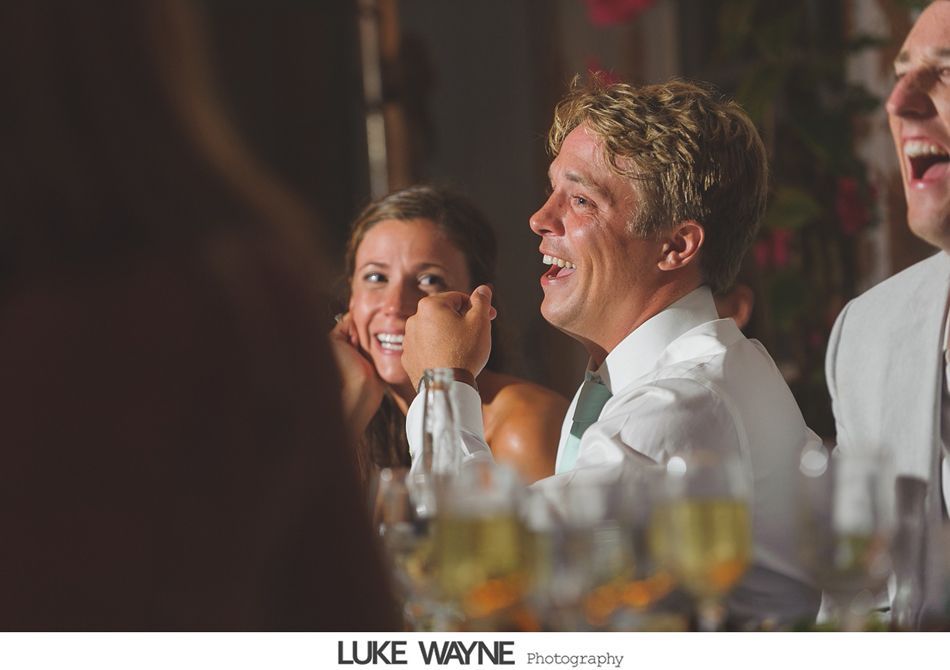 People laughing at a table during a celebration, with champagne glasses in the foreground.