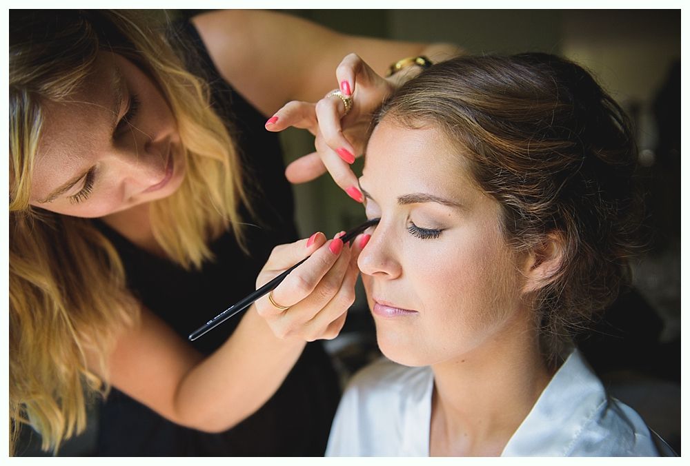 Groom and groomsmen on a beach, wearing suits. Groom in navy pants, others in khaki. All with blue ties, ocean in background.