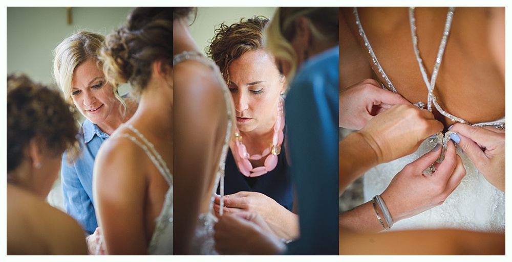 Bride and groom on rocky shoreline, ocean and blue sky background. Groom in suit, bride in white dress, looking at each other.