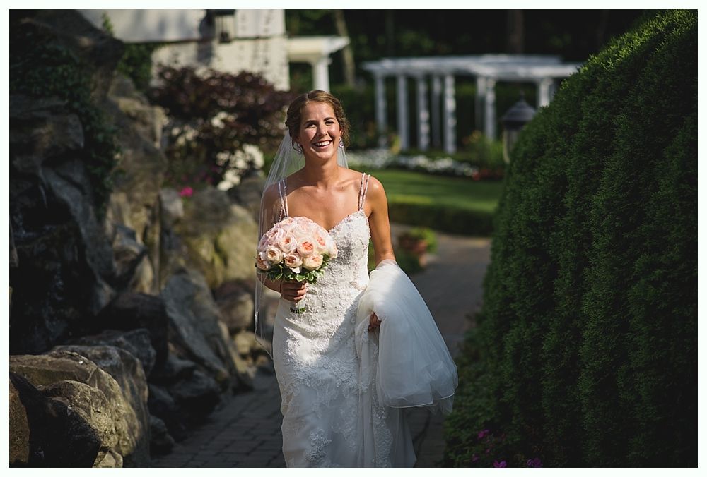 Bride with arms up, making a funny face, groom looking at his hand, cake cutting in background.