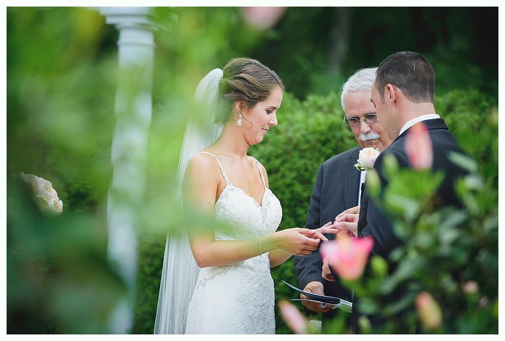 Bride with arms up, making a funny face, groom looking at his hand, cake cutting in background.