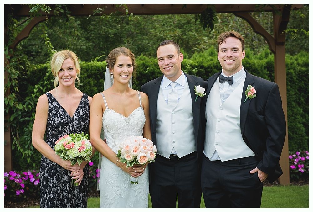 Bride with arms up, making a funny face, groom looking at his hand, cake cutting in background.