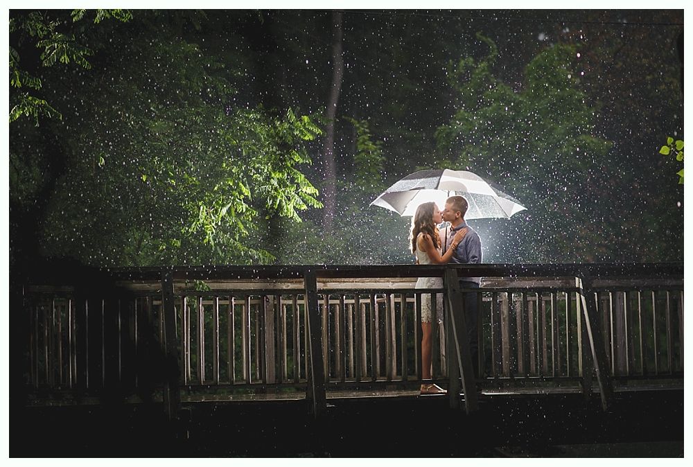 Bride and groom on rocky shoreline, ocean and blue sky background. Groom in suit, bride in white dress, looking at each other.