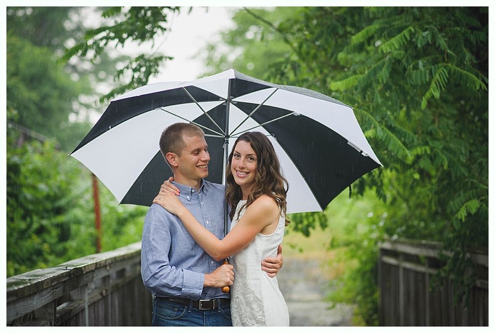 Bride and groom embrace on a beach. Ocean, blue sky, and tree branch in the foreground.