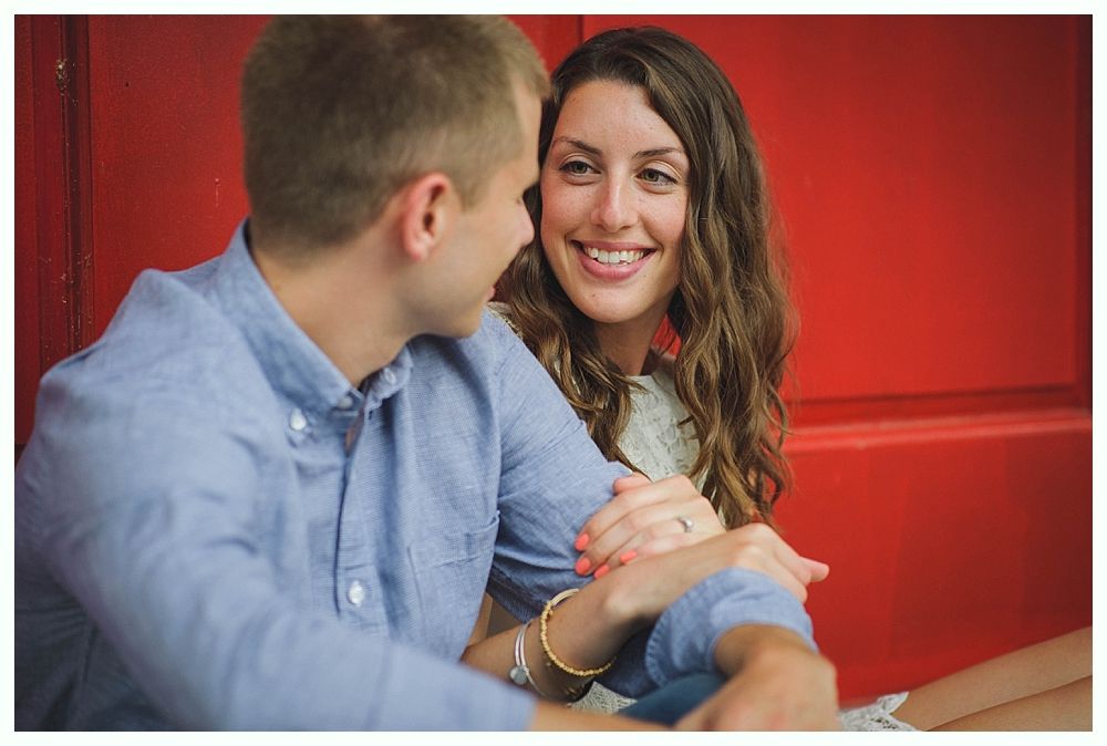 Bride with arms up, making a funny face, groom looking at his hand, cake cutting in background.