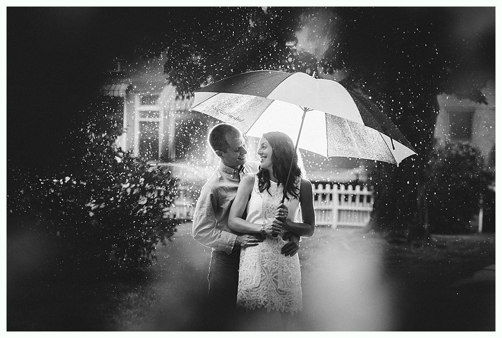 Bride with arms up, making a funny face, groom looking at his hand, cake cutting in background.