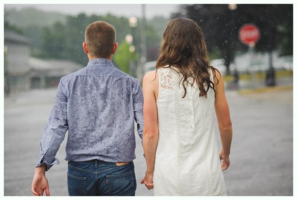 Bride with arms up, making a funny face, groom looking at his hand, cake cutting in background.