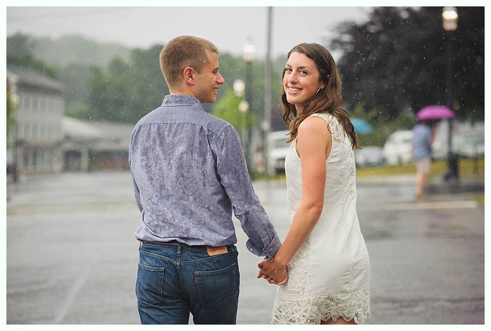 Bride with arms up, making a funny face, groom looking at his hand, cake cutting in background.