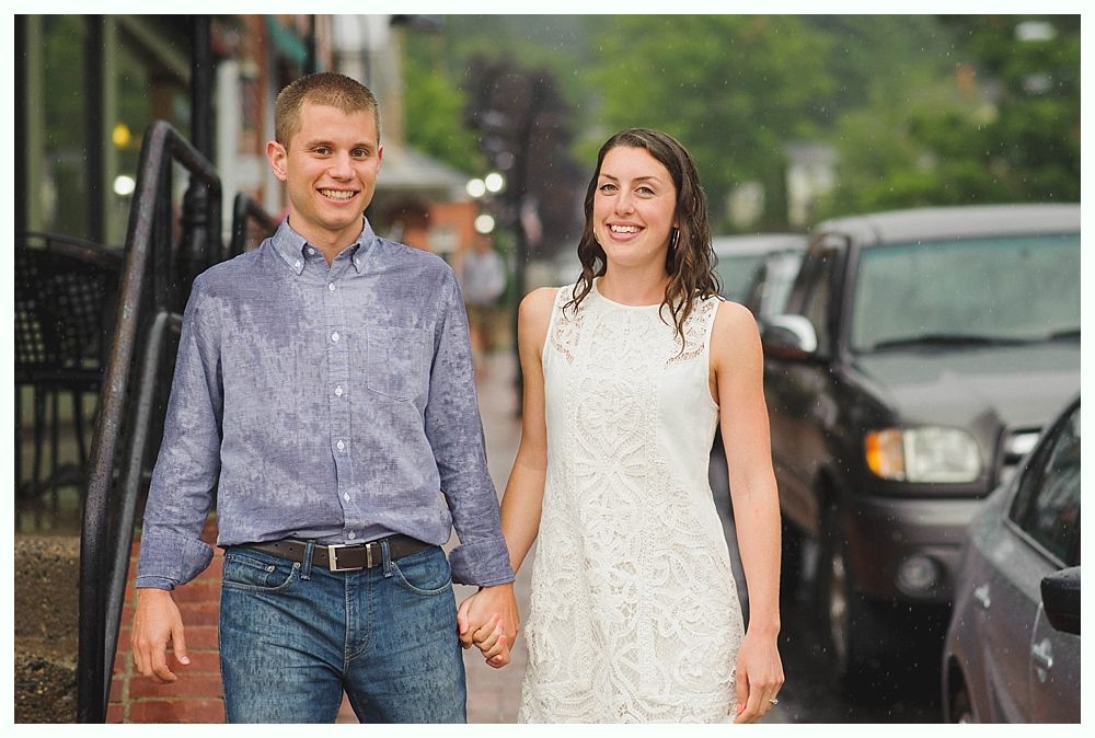 Bride with arms up, making a funny face, groom looking at his hand, cake cutting in background.