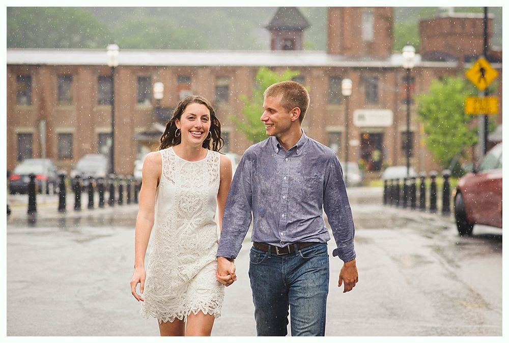 Bride with arms up, making a funny face, groom looking at his hand, cake cutting in background.