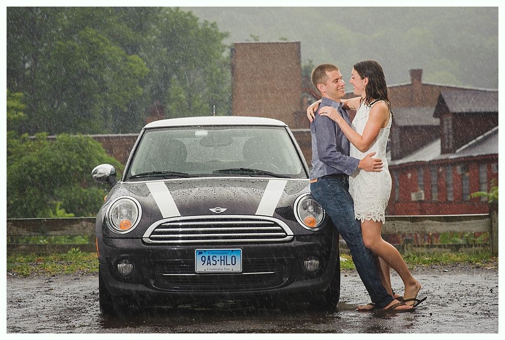 Bride with arms up, making a funny face, groom looking at his hand, cake cutting in background.