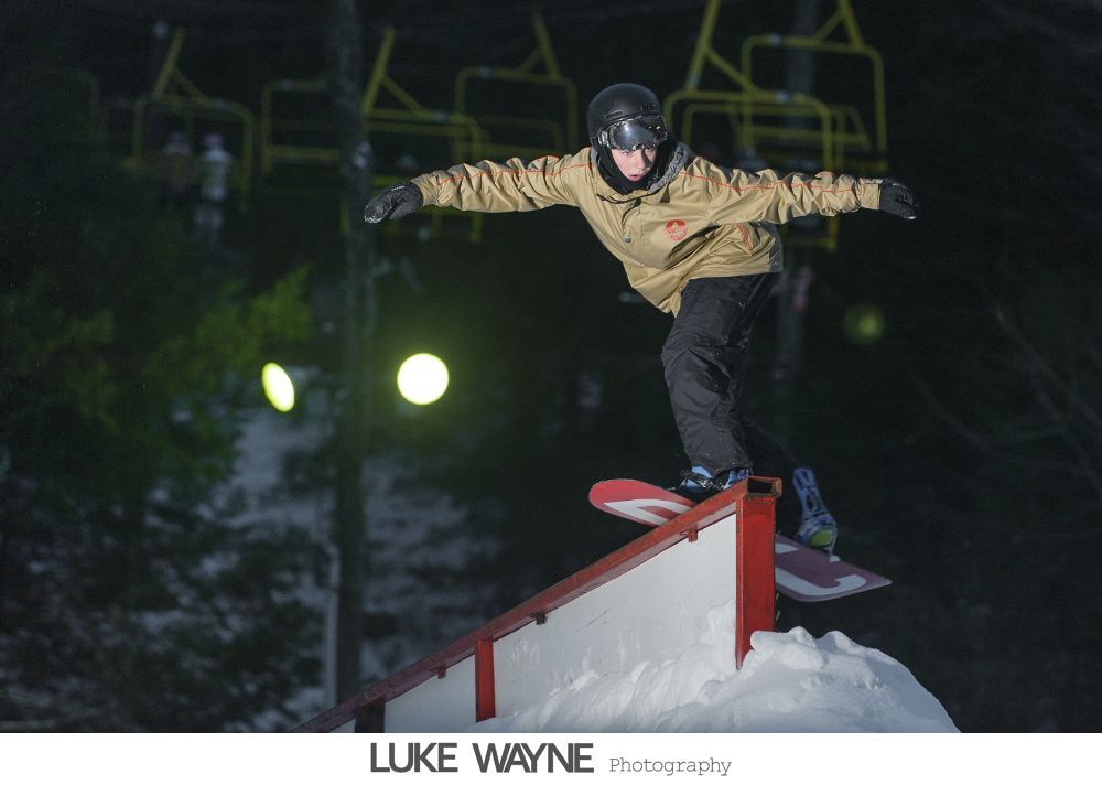 Wedding rings, bouquet, and embellished shoes arranged on dark blue fabric.