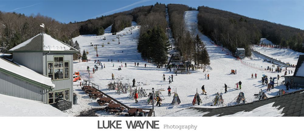 Man adjusting shirt cuffs, then smiling, wearing a gray suit with lavender bow tie and pocket square.