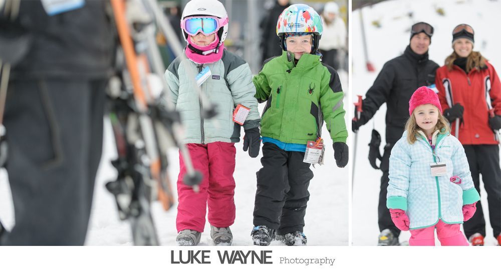 Two wedding dresses hanging in a window, with a chandelier and flowing fabric.
