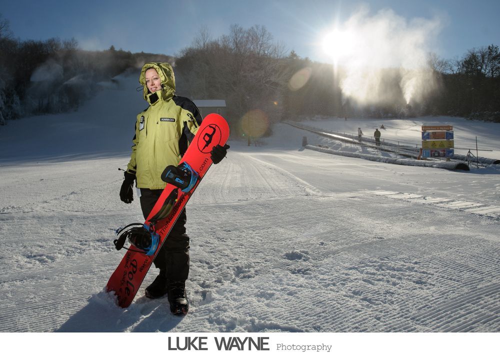 Wedding party toasting with champagne in a dimly lit bar, bride and groom center. Purple dresses, grey suits.