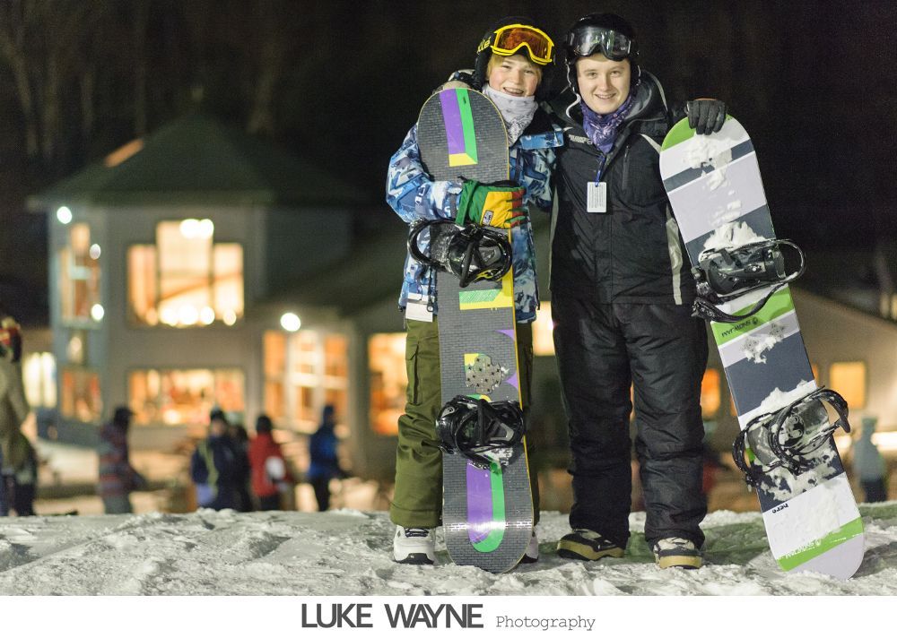 Bride and groom in wedding attire kissing in a dimly lit bar, next to a pool table.