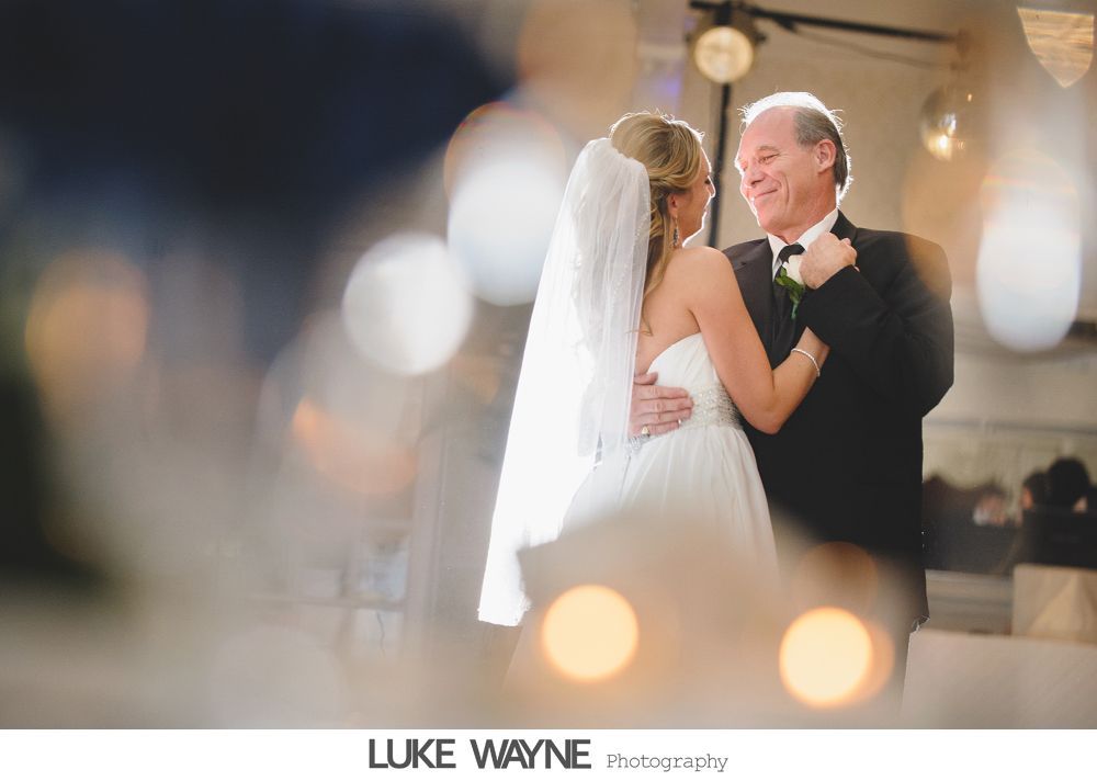 Bride and groom cross a city street, yellow school bus and traffic in the background.