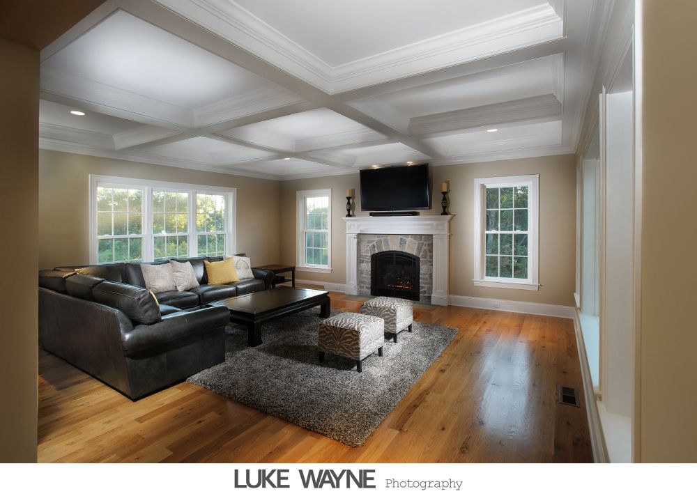 Bride in strapless white dress holding purple flowers, smiling. Dark background with archway.