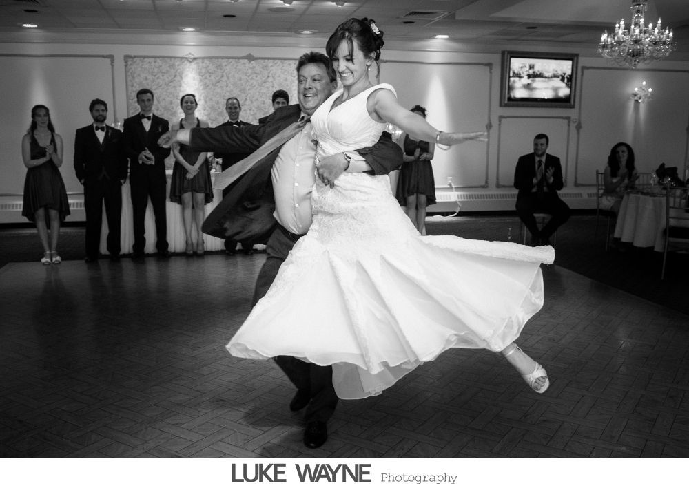 Bride and groom in wedding attire kissing in a dimly lit bar, next to a pool table.