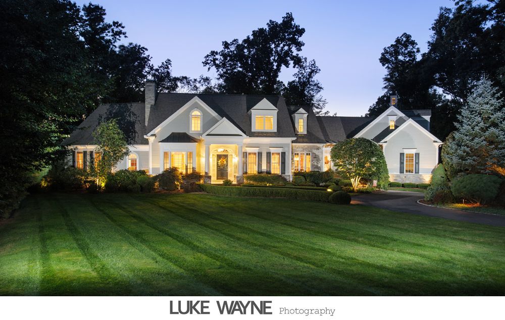 Couple in wedding attire embrace by open school bus door under a sunny sky.