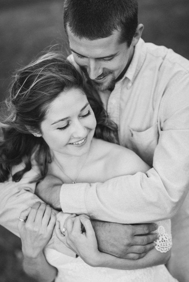 Couple embracing, smiling. Man in a button-down shirt, woman in a strapless dress. Black and white.