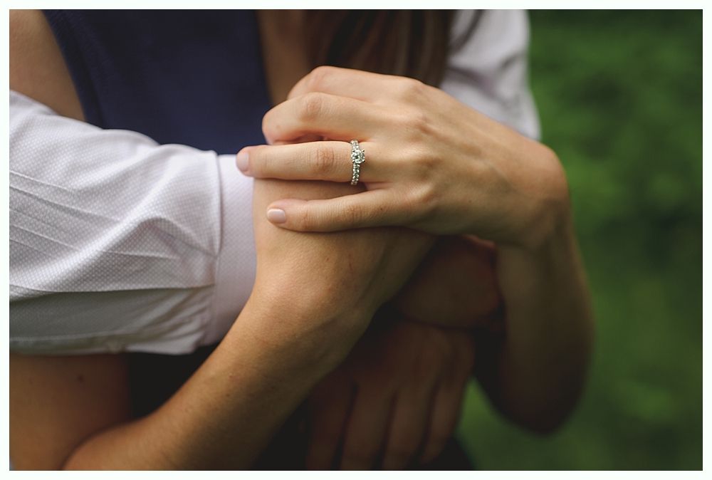 Bride in a white lace wedding dress, veil, and holding bouquet, smiles near window.