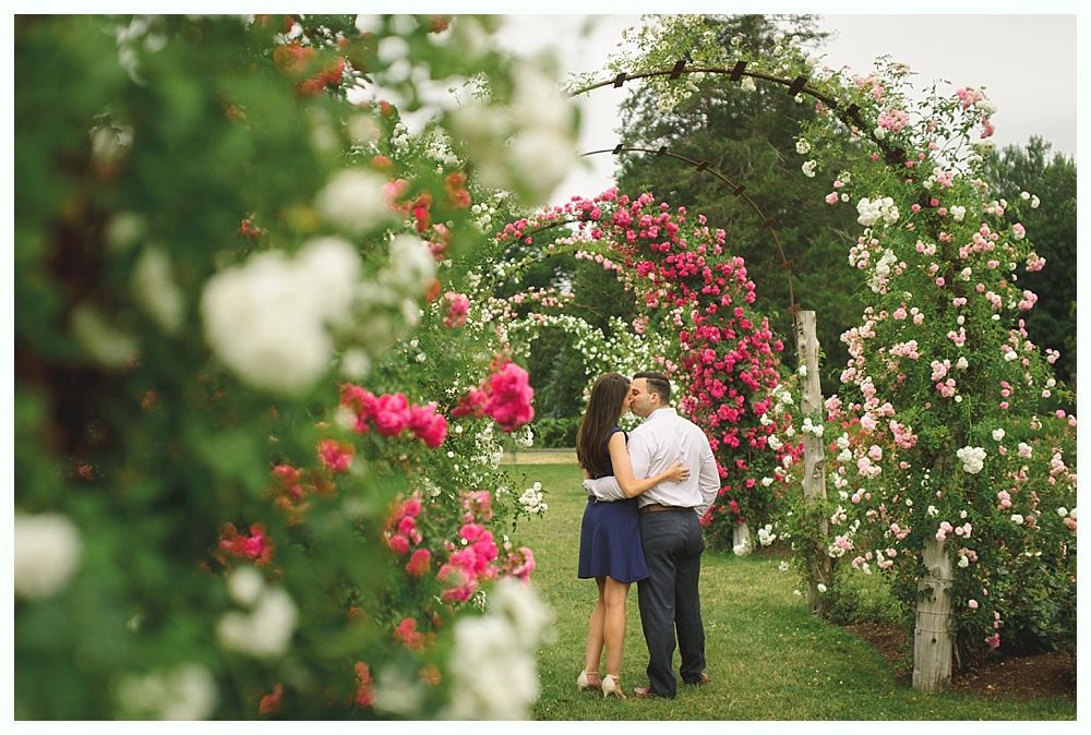 Wedding party on a bridge, smiling. Bride and groom centered, surrounded by bridesmaids and groomsmen, children.