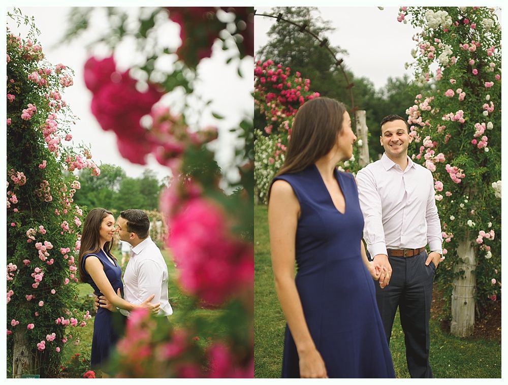 Wedding party laughs on a bridge. Bride holds flowers, wearing a veil. Groomsmen in suits. Bridesmaids in pink.