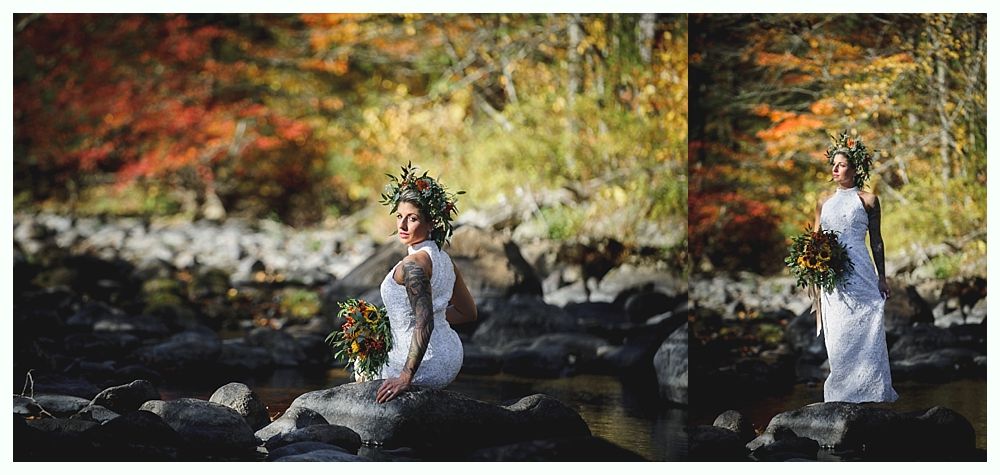 Bride in white dress with flower crown and bouquet, poses on rocks in a river, autumn foliage.