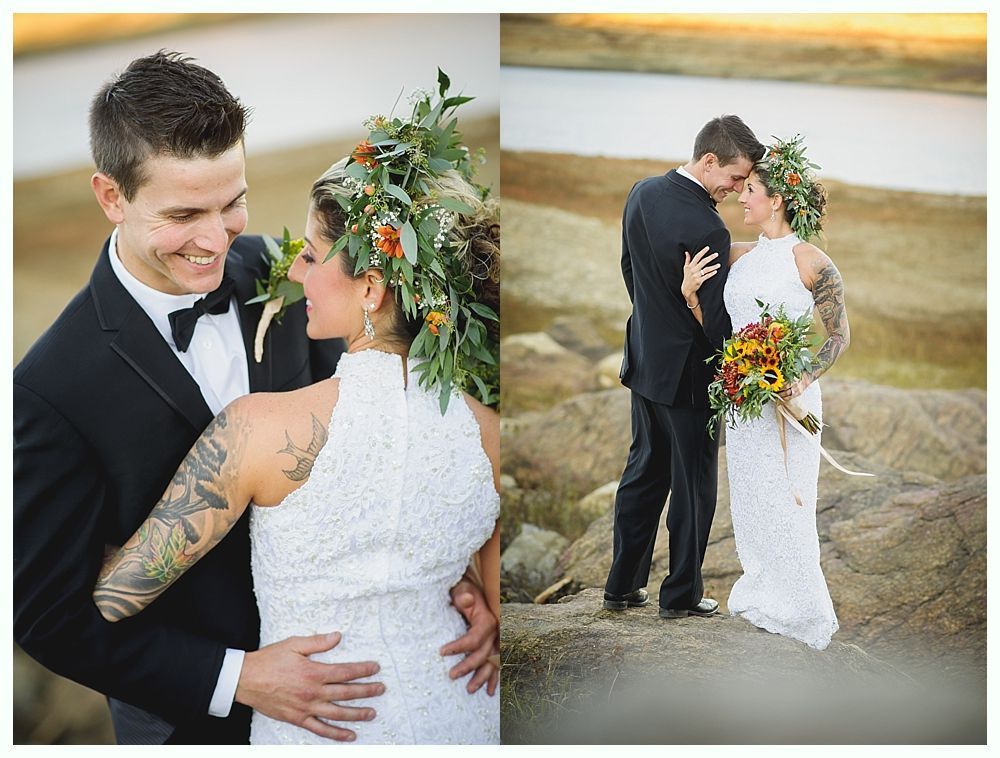 Wedding couple embracing outdoors; bride wears flower crown and white dress, groom in black tuxedo.