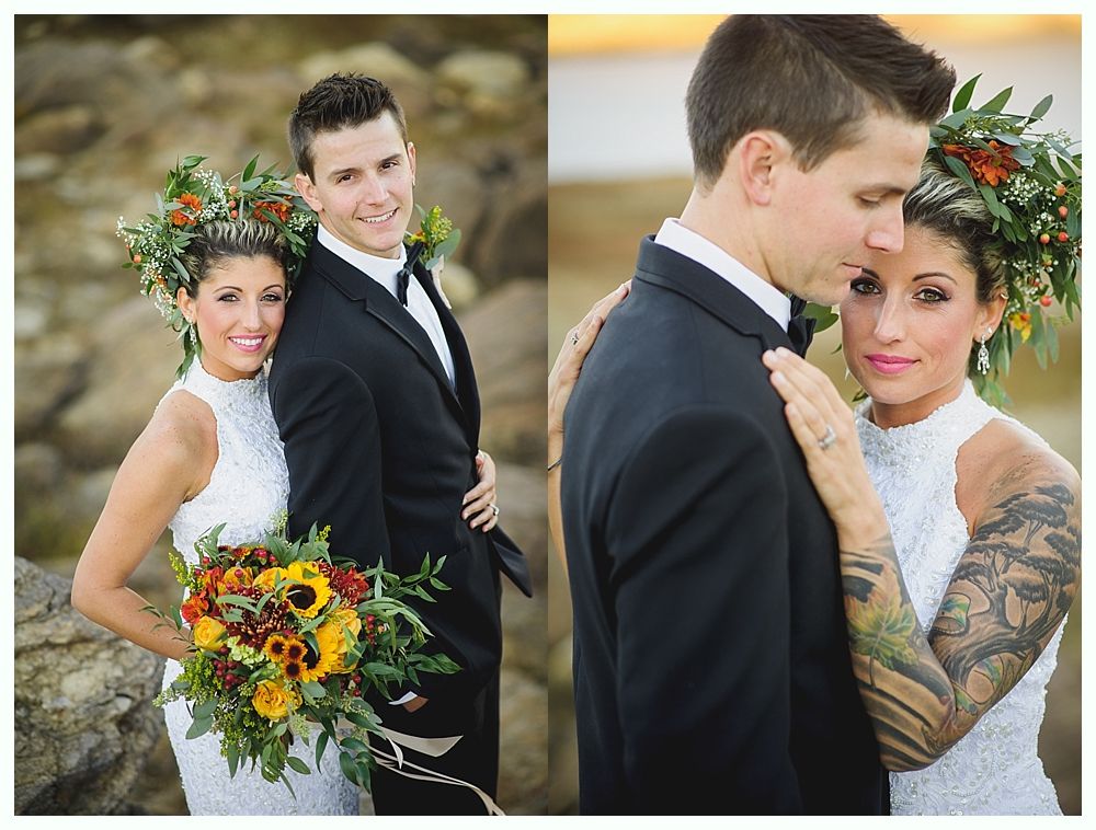Wedding couple in formal attire, posing outdoors. Woman with floral headpiece and tattoos, man in tuxedo, hugging.