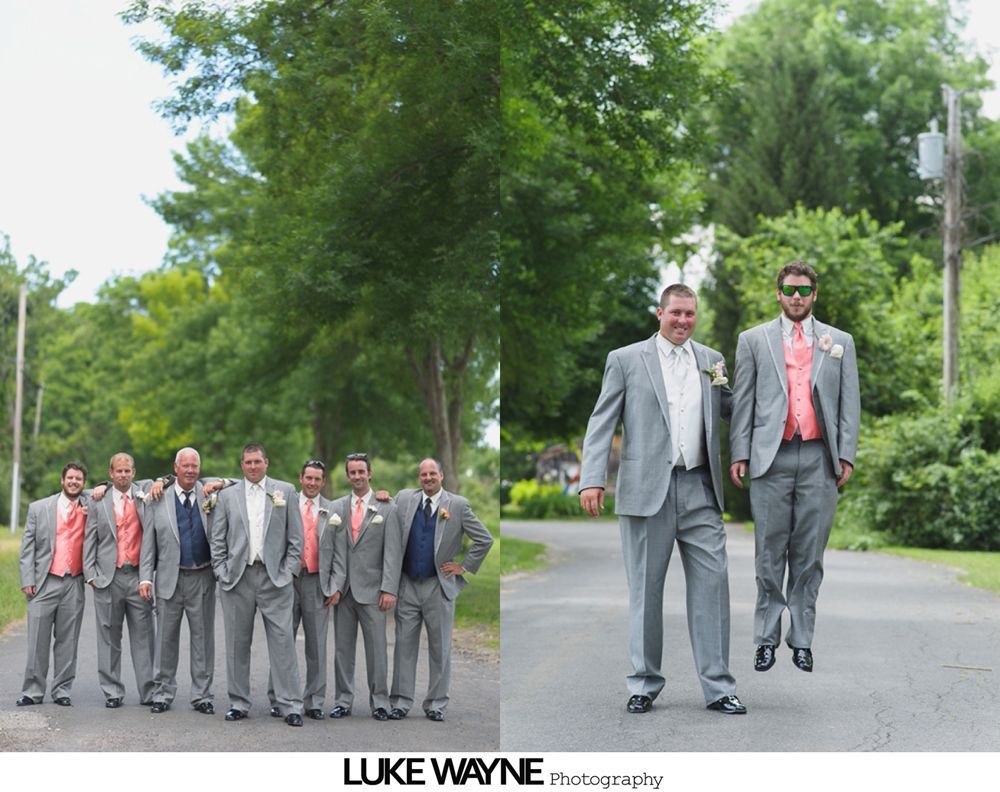 Groom in gray suit and bow tie smiles, posed with groomsmen, in front of yellow truck.