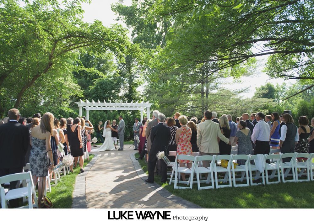 Wedding sign on an easel, surrounded by flower arrangements on chairs.