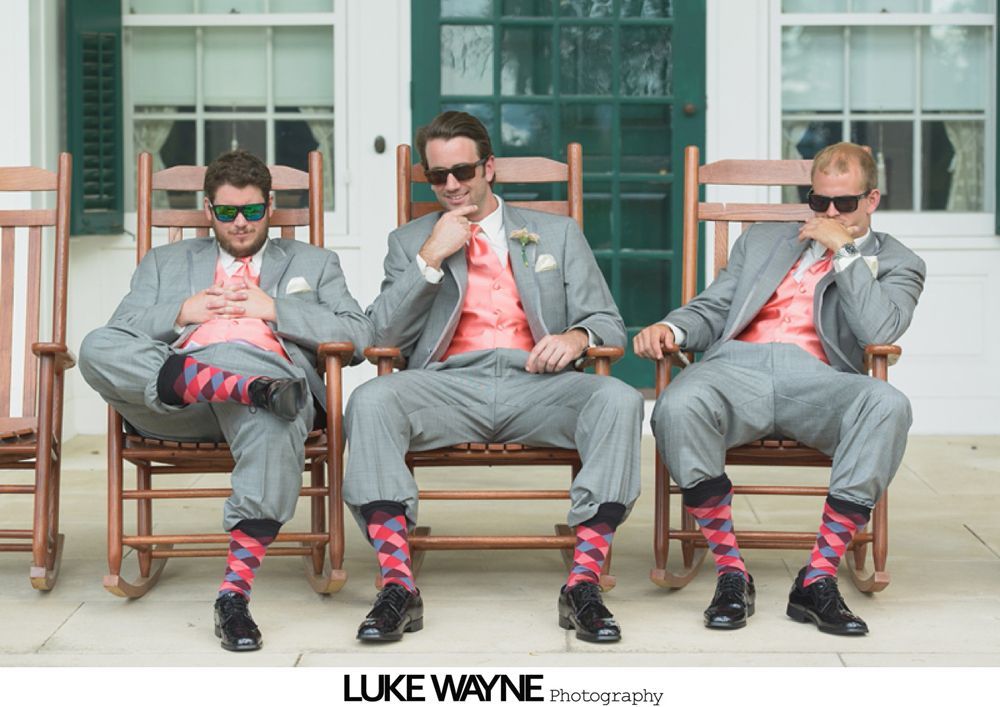 Wedding party posing on a rural road; bride and bridesmaids in pastel dresses, groomsmen in gray suits.