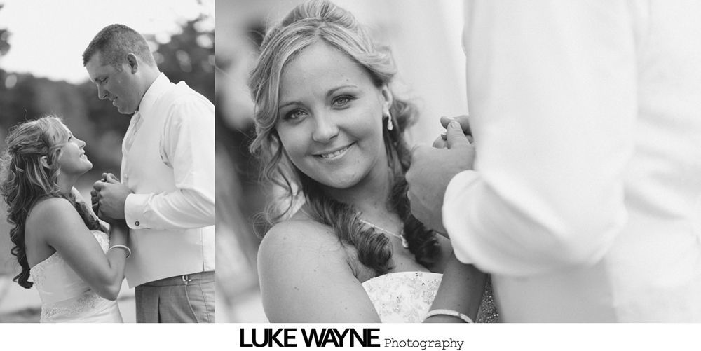 Bride and groom on a road. Man hugs woman, smiles, and holds flowers.