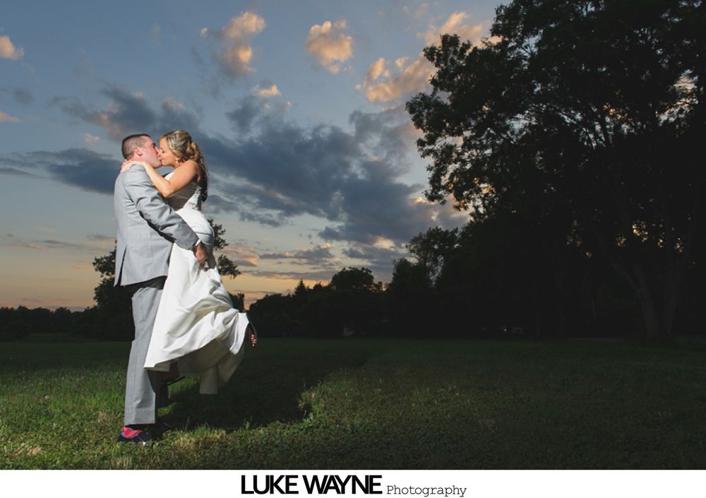 Bride and father dance at wedding reception, smiles and chandeliers overhead.