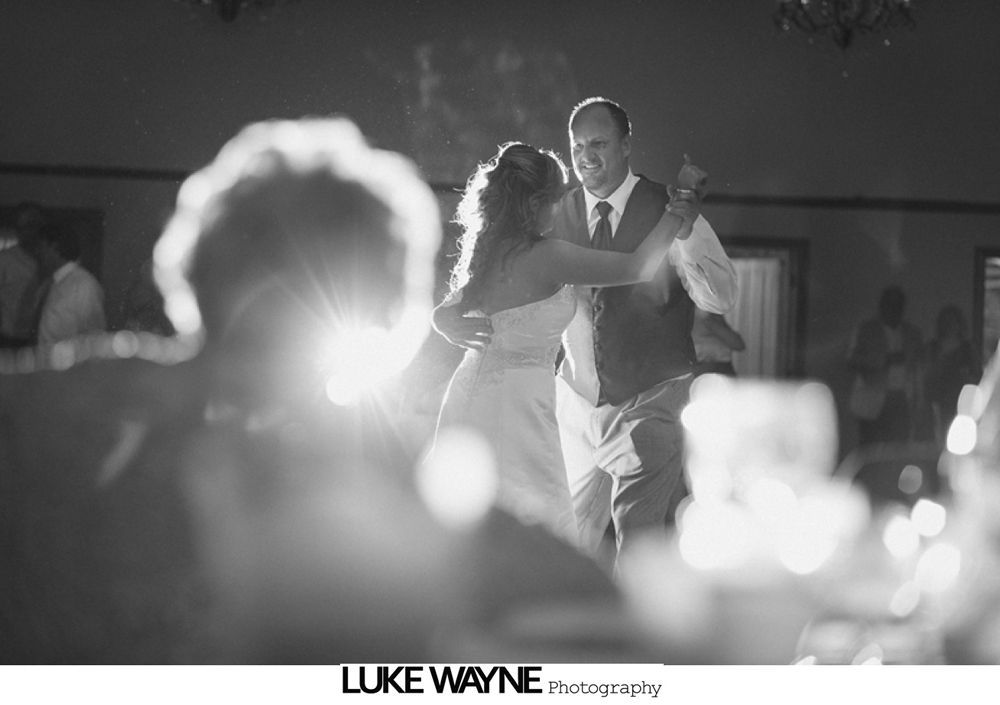 Wedding couple kissing under an umbrella in the rain.
